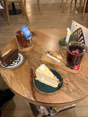 Kubki gorącej herbaty i ciasto w ciepłym świetle świec – chwila zatrzymania przed świętami.